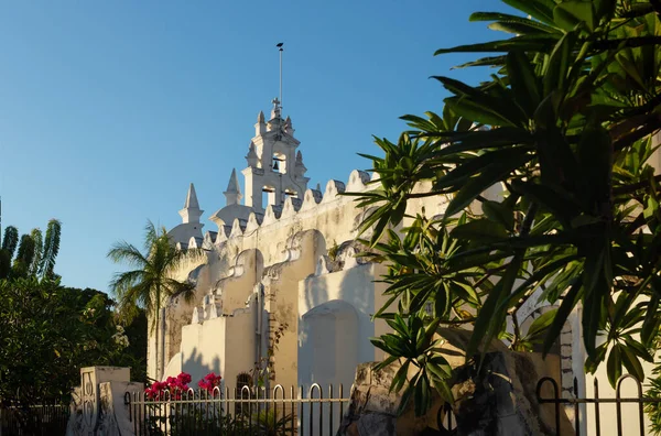 Havari Kilisesi 'nin Parroquia de Santiago Apostol' u, son güneş altında tropikal bitkilerle, Merida, Yucatan, Meksika 'da süslü çan kulesi olan eski Roma Katolik kilisesi.