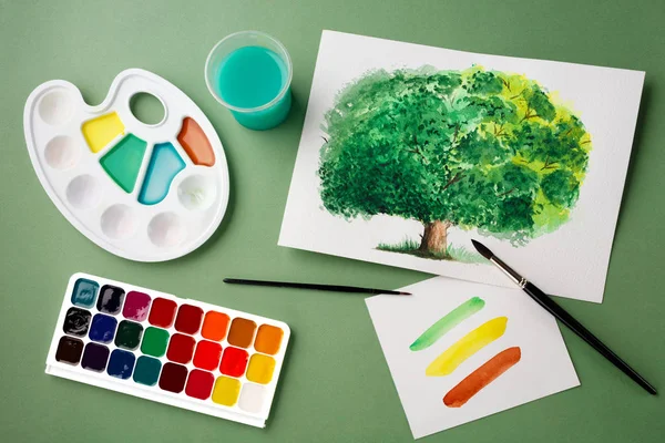 Painting tools in art studio on green background. School concept, creativity art concept, watercolor painting hobby concept.