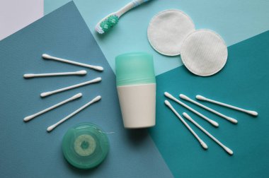 Farklı tonlarda mavi arka plan üzerinde yüz ve kulaklar için tomurcuklar için bir deodorant, pamuk pedleri, fırça diş ve diş ipi.