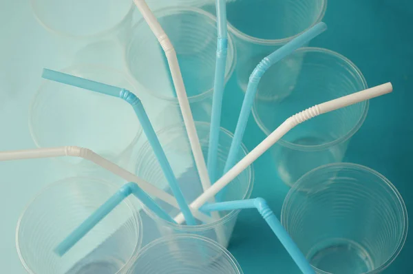 Turkuaz arka plan meyve suyu ve kokteyller için mavi ve beyaz plastik saman borular. Bardak içinde plastik borular