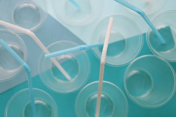 Beyaz ve turkuaz arka planda pipetler tübüllü tek kullanımlık plastik bardaklar. Plastik kavramı. Seçici odaklama.