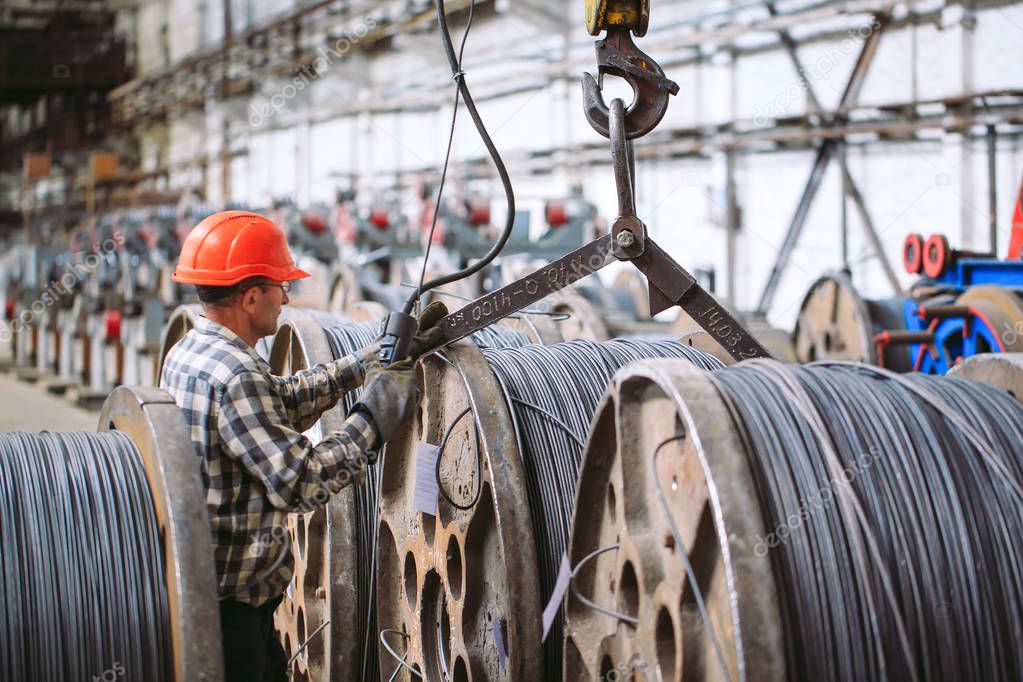 Wire rod, fittings in warehouses. worker alongside a bundle with catalkoy. industrial storehouse at the metallurgical plant.