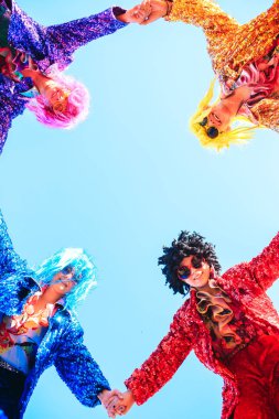 Mavi gökyüzüne karşı poz veren ayaklıklar üzerinde gençler.