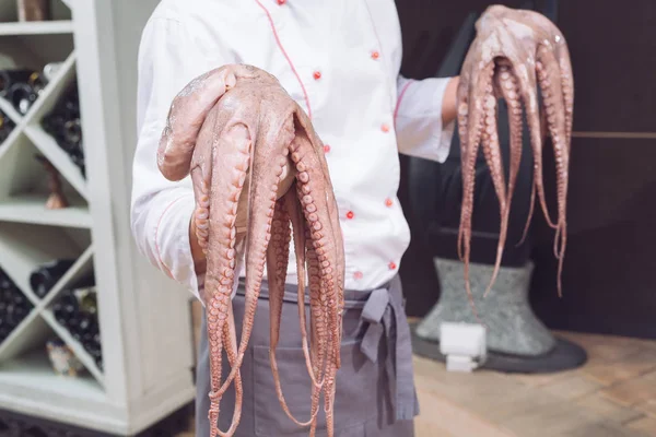 closeup of chef holding fresh raw octopus.