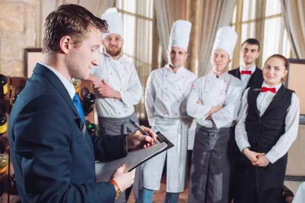 restaurant manager and his staff in kitchen. interacting to head chef in commercial kitchen.