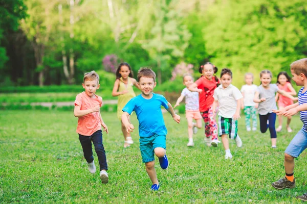 多くの異なる子供 男の子と女の子のカジュアルな服装で日当たりの良い夏の日 公園で走っています — ストック写真