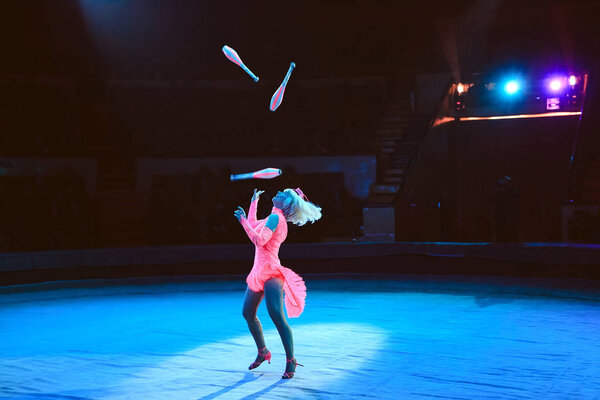 A woman juggles in the circus arena.