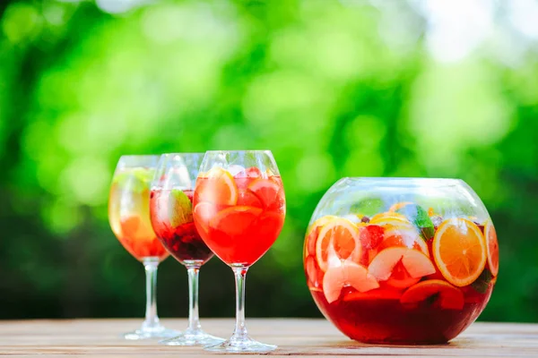 Summer cocktail. Fruit cocktail on green background. Citrus fruits, berries, strawberries, blueberries, mint, ice