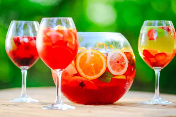 Summer cocktail. Fruit cocktail on green background. Citrus fruits, berries, strawberries, blueberries, mint, ice