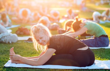 Bir grup genç gün batımında Park'ta yoga yapıyor..