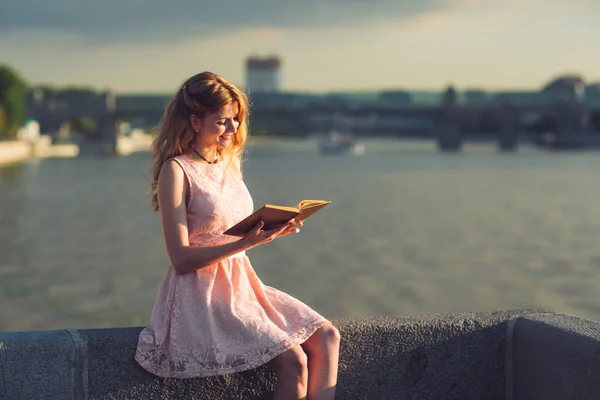 一个年轻女孩在河岸上看书 — 图库照片