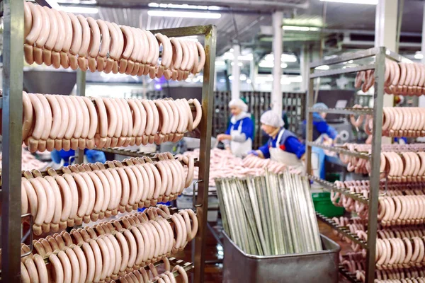 Butchers processing sausages at meat factory.