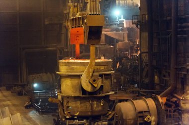 Çelik fabrikasında metalin erimesi. Eriyen ocakta yüksek sıcaklık. Metalürji endüstrisi. Metal borular üreten bir fabrika. Metali kalıplara doldurmak için kova.