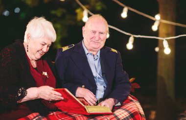 Mutlu anılar. Mutlu yaşlı çift fotoğraf ile albüm izlerken kanepede oturan.