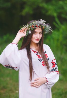 Genç bir kızla Slav görünüm kır çiçekleri yaz ortası üzerinde bir çelenk.