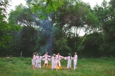Midsummer. Slav giysileri içinde gençler ormanda bir şenlik ateşi etrafında dans daire.