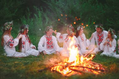 Yaz gecesi. Şenlik ateşi oturan Slav giysili gençler.