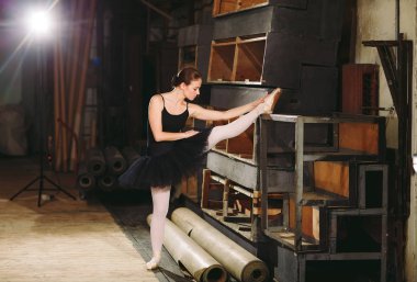 Young ballerina in black dress trains behind the scenes. clipart