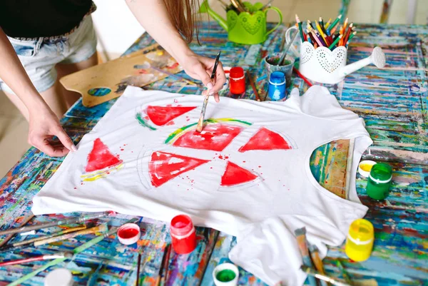 Drawing on clothes. Girl draws on a white T-shirt.