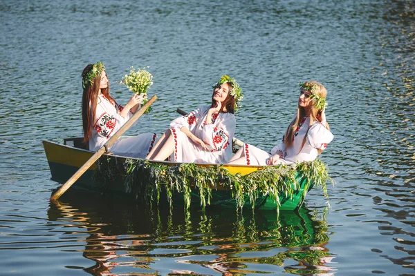 国民的衣装を着た若い女の子は 葉と成長で飾られたボートで航海します イワン クパラのスラヴォニック ホリデー — ストック写真