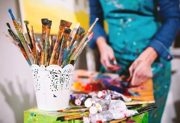 brushes in pot and Girl on background in Painting Studio