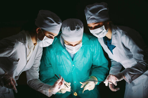 The surgeon makes an operation in a dark room.