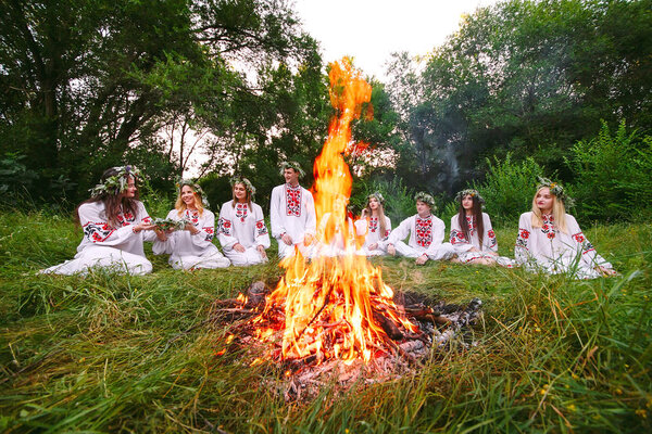 В середине лета. Молодые люди в славянской одежде сидят в лесу у костра
.