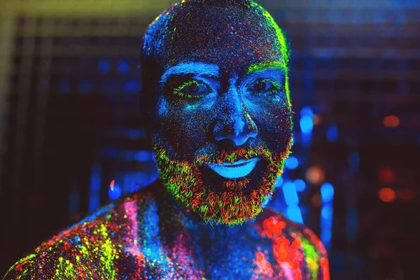 Portrait of a bearded man painted in fluorescent powder.