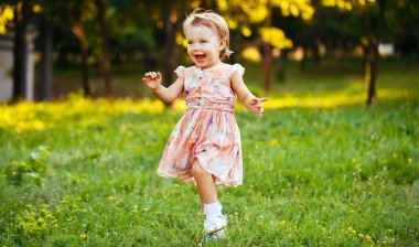 Parkta çim üzerinde çalışan mutlu sevimli küçük kız. Mutluluk