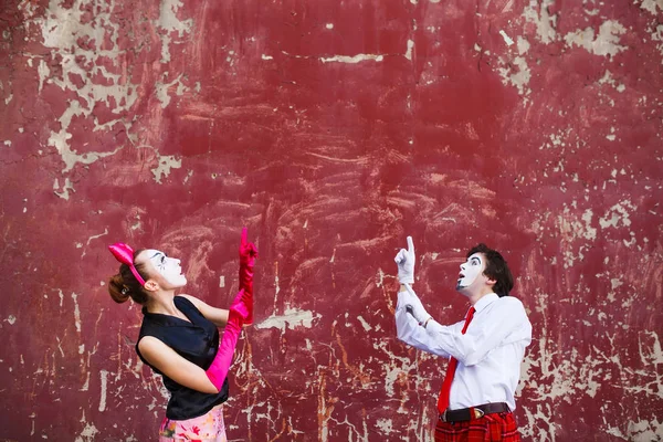 Couple mimes point to the top on a red wall. — Stock Photo, Image