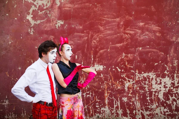 Couple mimes regardant de côté sur le fond d'un mur rouge . — Photo