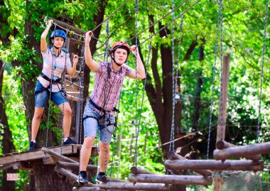 Yüksek telli parka tırmanma macerası - insanlar dağ kaskı ve güvenlik ekipmanları ile rotalarında