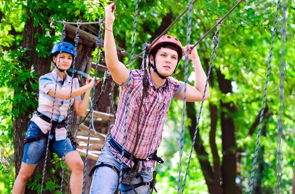 Adventure climbing high wire park - people on course in mountain helmet and safety equipment — Stock Photo, Image