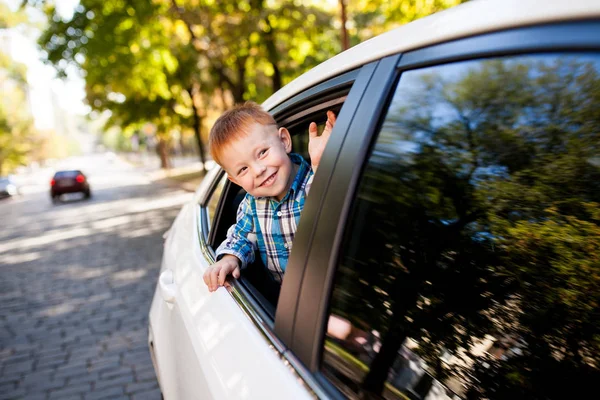 Adorable niño en el coche. Chico sonriente mira por la ventana del coche . —  Fotos de Stock