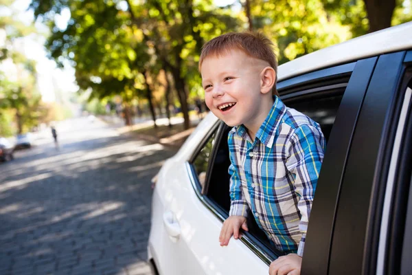 Entzückender kleiner Junge im Auto. Lachender Junge blickt aus dem Autofenster. — Stockfoto