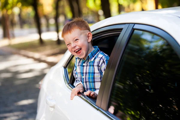 Entzückender kleiner Junge im Auto. Lachender Junge blickt aus dem Autofenster. — Stockfoto