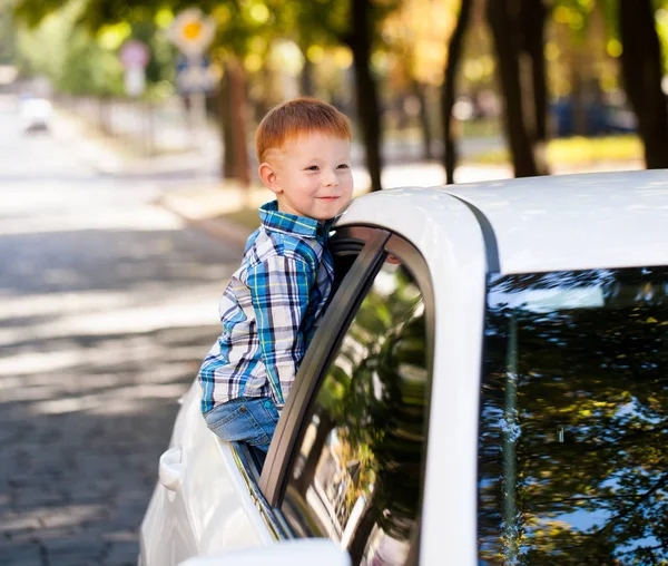 Милый мальчик в машине. Смеющийся мальчик смотрит в окно машины . — стоковое фото