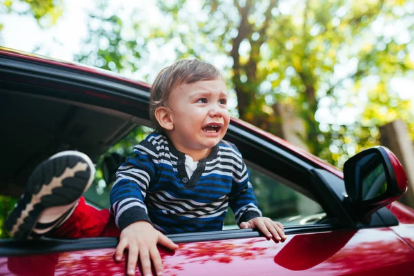 Llorando niño en el coche. El chico está llorando y quiere salir de la maniche — Foto de Stock