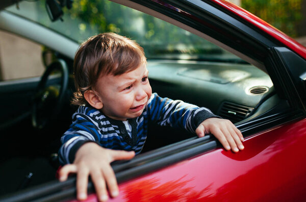 Crying baby boy in car. The boy is crying and wants to get out of the maniche