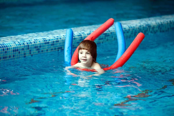 Kind schwimmt im Pool. Kleiner Junge lernt Schwimmen im Pool — Stockfoto