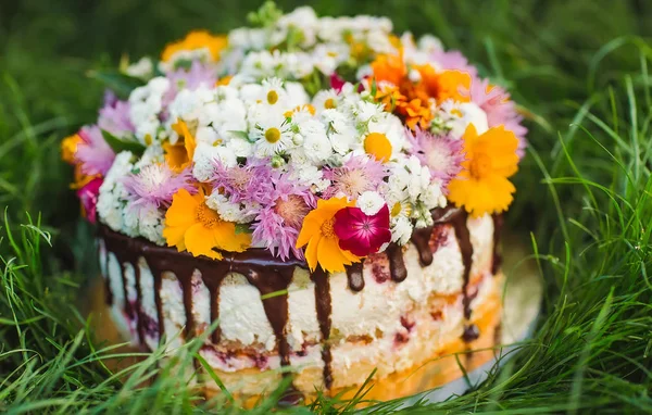 Naked cake decorated with flowers on the grass.