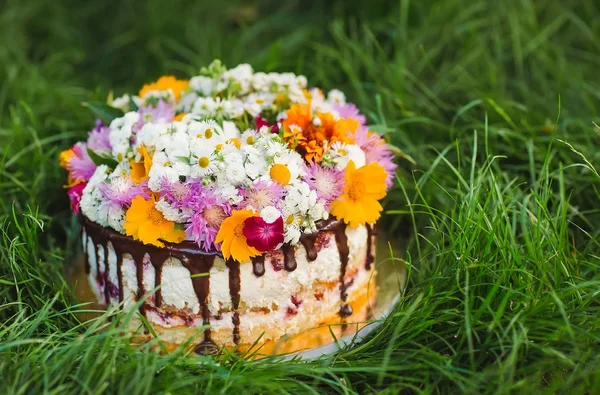 Naked cake decorated with flowers on the grass.