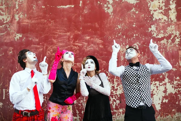 Four mimes point to the top on a red wall — Stock Photo, Image