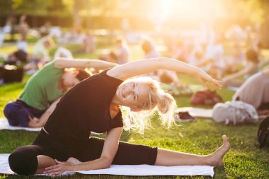 Yeşil çimenlerin üzerinde yoga kadını. Büyük grup