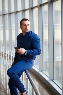 Havaalanı salonunda cep telefonu ile genç işadamı.