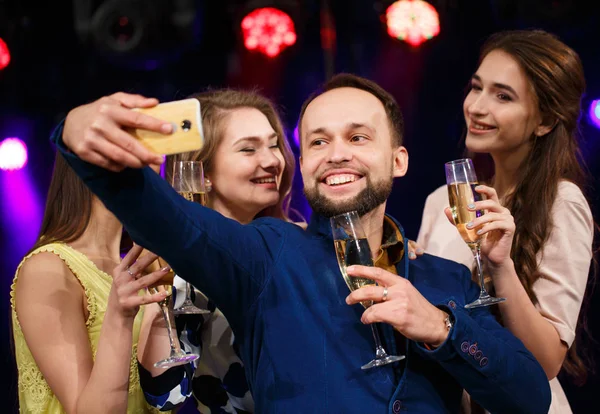 Party, Urlaub, Technik, lächelnde Freunde mit Champagnergläsern und Smartphone beim Selfie im Club. — Stockfoto