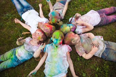 Çocuklar çimlerin üzerinde yatar. Holi festivalinin renklerine boyanmış çocuklar çimlerin üzerinde yatıyor.