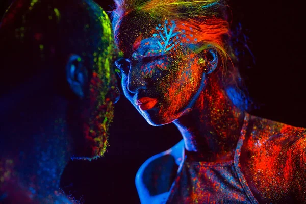 Retrato de un par de amantes pintados en polvo fluorescente . — Foto de Stock