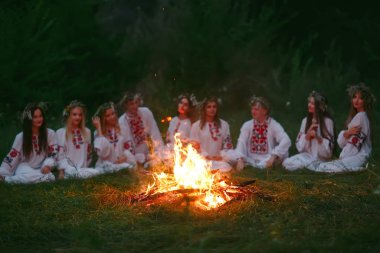 Yaz gecesi. Şenlik ateşi oturan Slav giysili gençler
