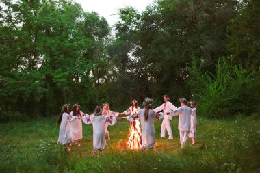 Midsummer. Slav giysileri içinde gençler ormanda bir şenlik ateşi etrafında dans daire.